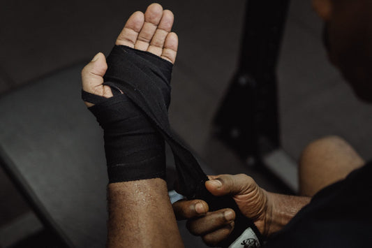 Boxer wrapping his hands with black cotton hand wraps before training