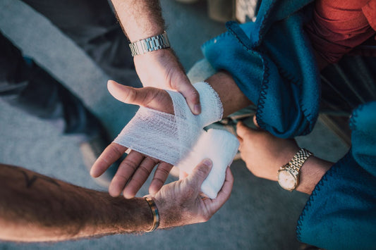 Hands applying a gauze bandage to an injured hand