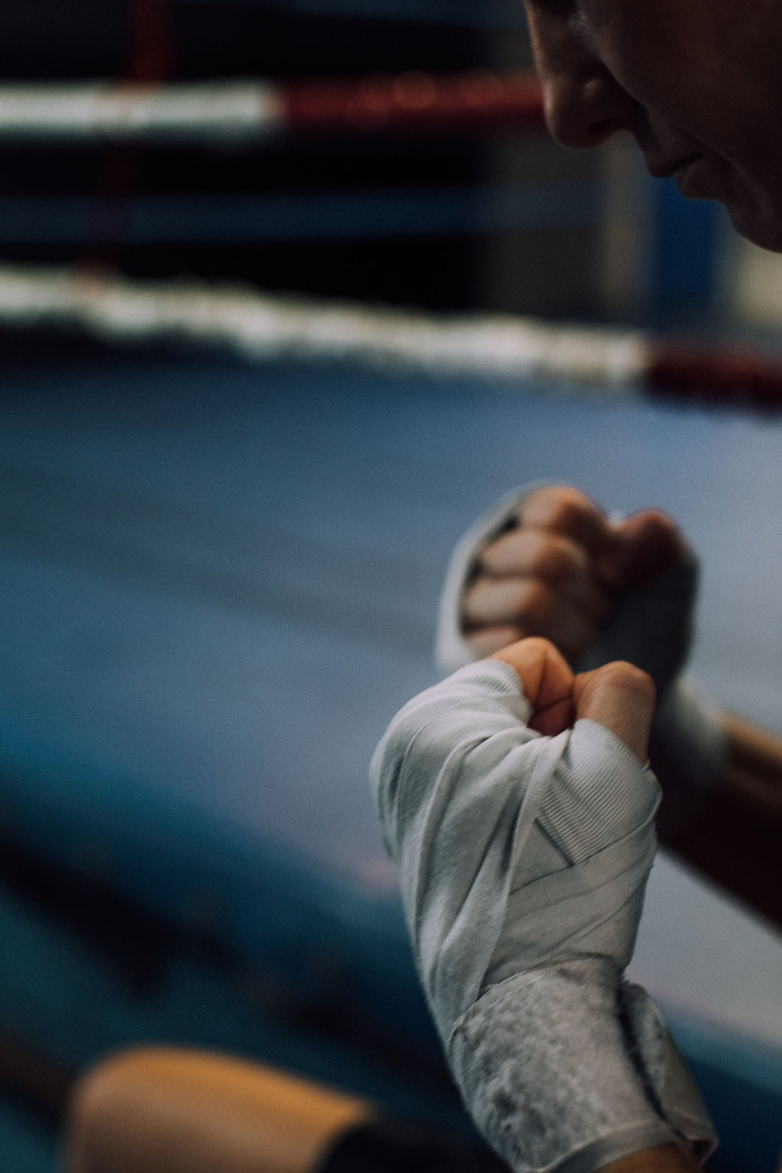 Boxer's wrapped hands resting on the ring apron
