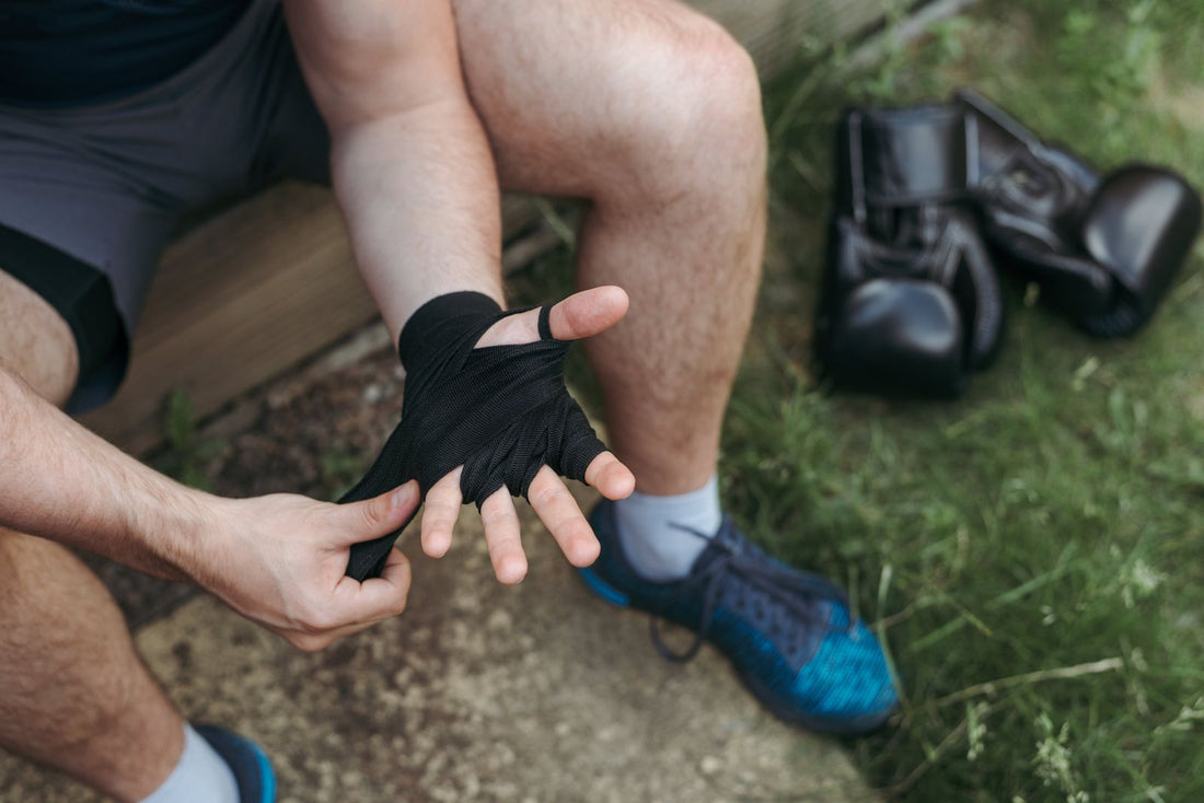 Boxer wrapping his hands with gloves resting on the ground nearby