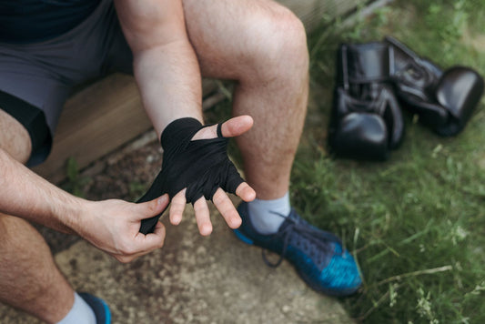 Boxer wrapping his hands with gloves resting on the ground nearby