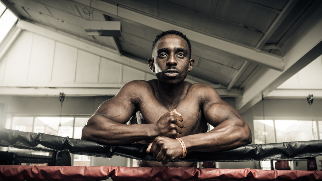Mature boxer leaning on ring ropes in a bright gym