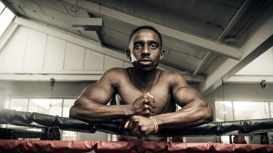 Mature boxer leaning on ring ropes in a bright gym