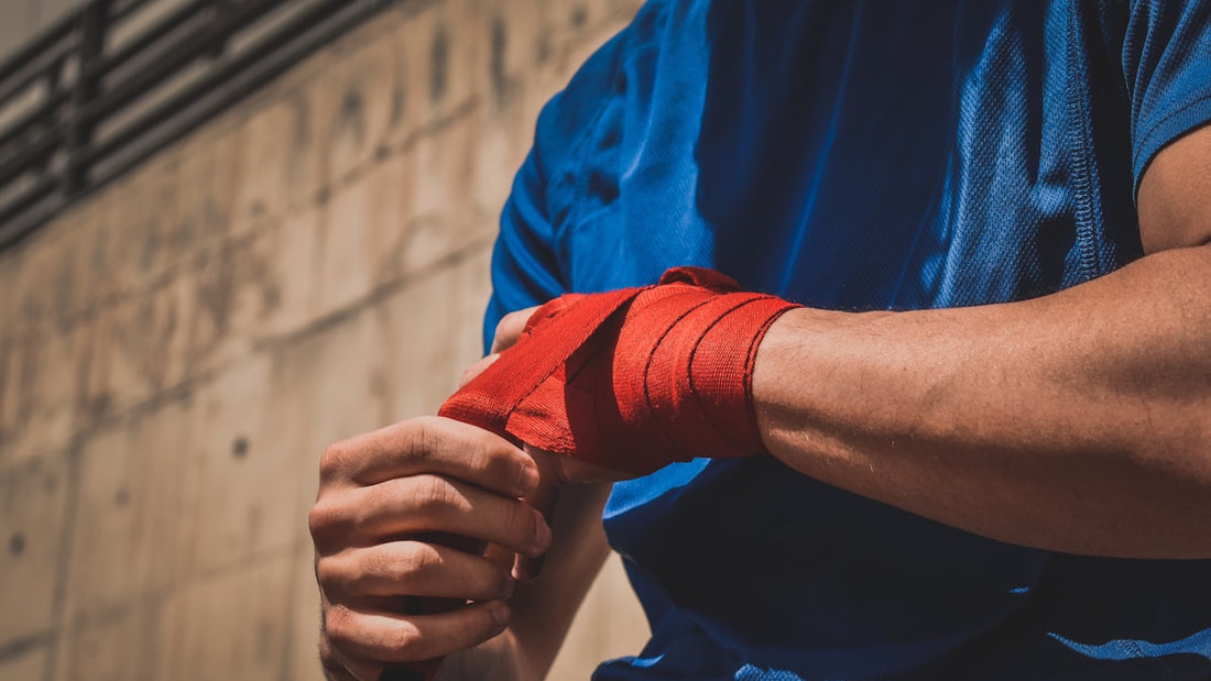 Red boxing hand wraps being wrapped tightly around a fighter's knuckles