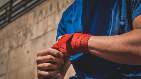 Red boxing hand wraps being wrapped tightly around a fighter's knuckles