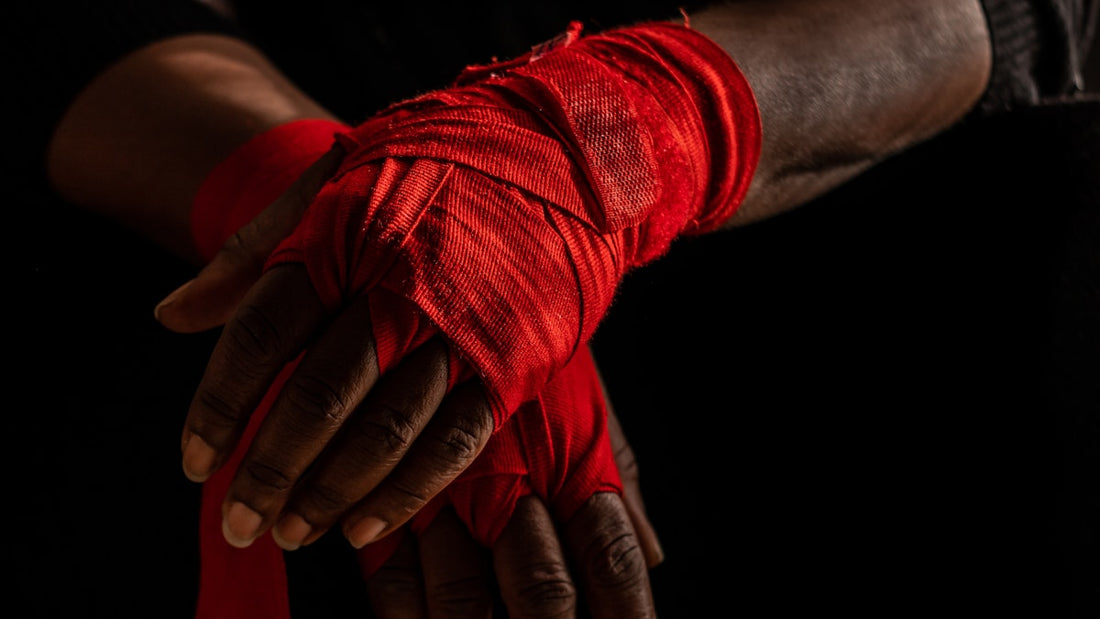Red boxing hand wraps pressed together against a black background