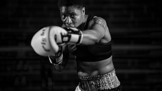 Black and white photo of a strong female boxer mid-punch in training