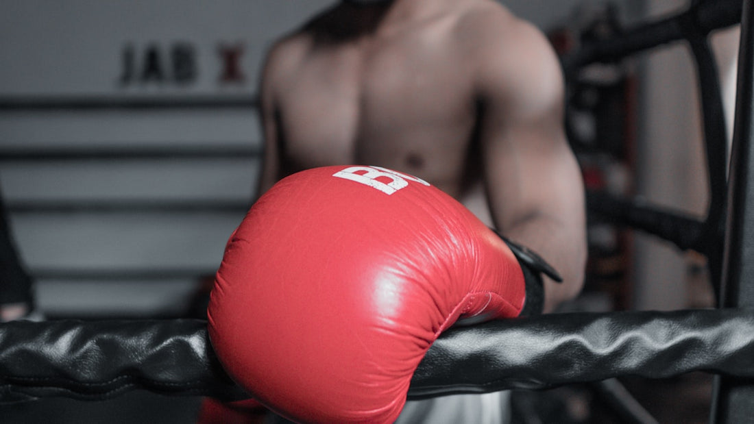 Red boxing gloves resting on ring ropes in a boxing gym