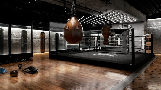 Dark moody boxing gym with heavy bags and ring