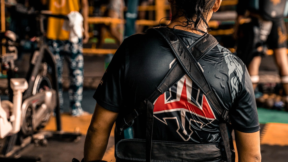 Fighter from behind looking into a busy boxing gym with ring and heavy bags