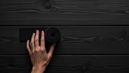Hand rolling up a black boxing hand wrap on a dark wooden surface