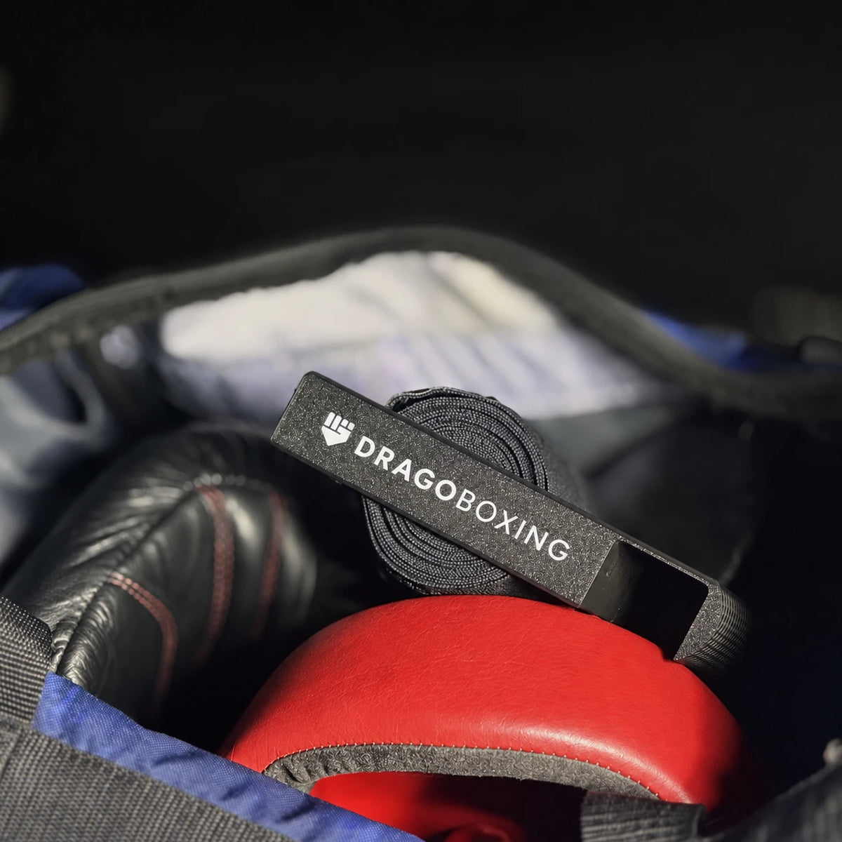 Drago Roller packed in a gym bag on top of rolled hand wraps, gloves and headgear